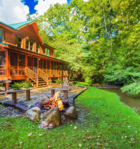 outdoor firepit next to a river behind a cabin
